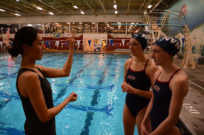 Coach Hayan Kim (left), of Fairfax, gives Robinson junior Jackie Hafner (center) and Woodson junior Margot Baden (right) technique advice for their duet routine.
