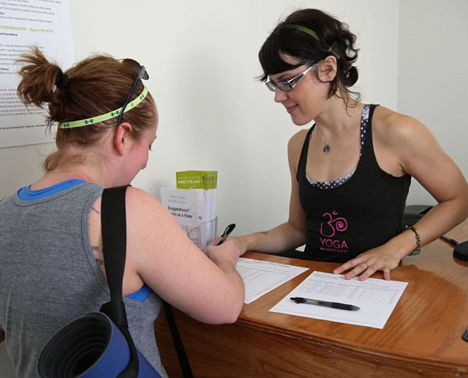 Laura Schwartz, director of programming at Mind the Mat yoga studio in Del Rey, beckons Danielle Locher to step up and sign in for the Flow 1 class.