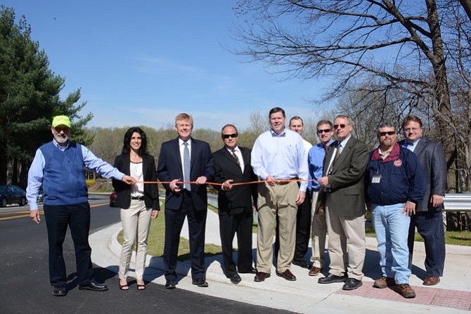 From left, Lee Schmidt, Burke Ponds trustee; Renée Mumford, Burke Landings trustee; Supervisor John Cook (R-Braddock); Paul Viano, Burke Centre Station community manager; Patrick Gloyd, Burke Centre executive director; Tim Conley, Fairfax County Department of Transportation; Chris Wells, Fairfax County Department of Transportation; James Horstman, Fairfax County Utilities Design & Construction; Ken Atkins, Fairfax County Utilities Design & Construction and John Honnick, Fairfax County Land Acquisition, cut the ribbon officially opening a new stretch of sidewalk along Burke Commons Road.