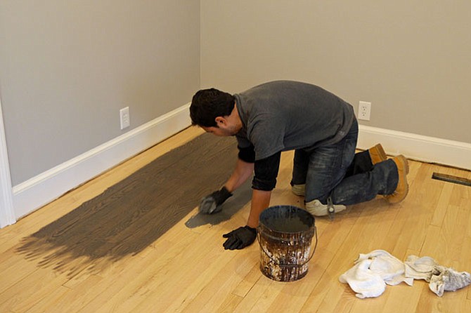 Roberto Melgar from M&M Floors puts test stains on the hardwood floors to match the walls.