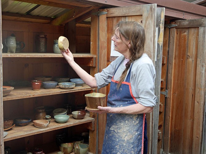 Linda Johnson points to finished bowls and cylinders that have been bisque-fired in an electric kiln over a four-day period, glazed and fired again at 2,000 degrees. Johnson has been teaching pottery at Glen Echo summer camps since the early 1970s when the camp began.