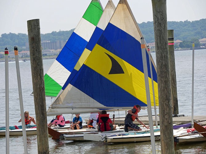 Beginning Sunfish classes sail from the dock on a summer morning to practice the day’s maneuvers.