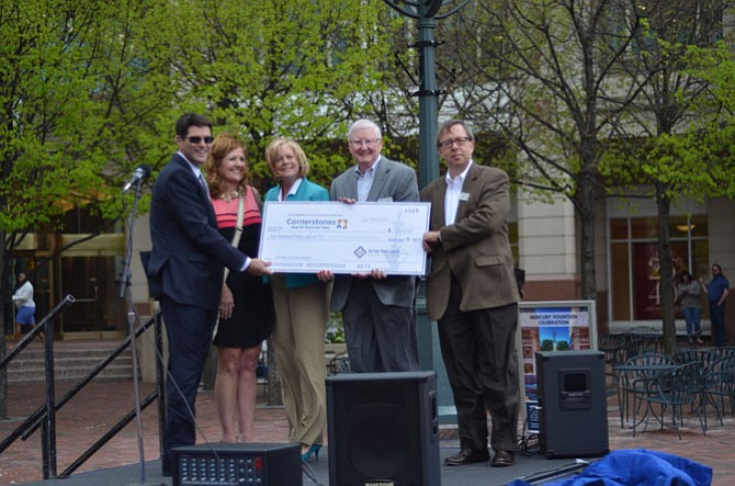 Reston Town Center Association executive director Robert Goudie (left) with representatives of the non-profit Cornerstones at Reston Town Center. All of the coins collected in the fountain in 2014 were donated to the organization Cornerstones.