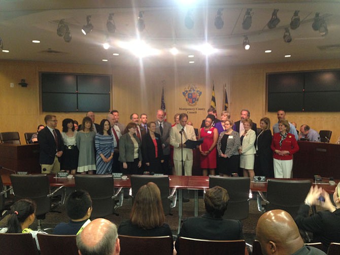 Montgomery County Council Member Roger Berliner (center) reads a proclamation saluting small business owners during a County Council meeting