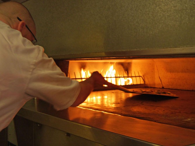 Buchholz pops the mushroom pizza into the oven for 4-6 minutes. The oven floor is 500 degrees with 800 degrees and the top.
