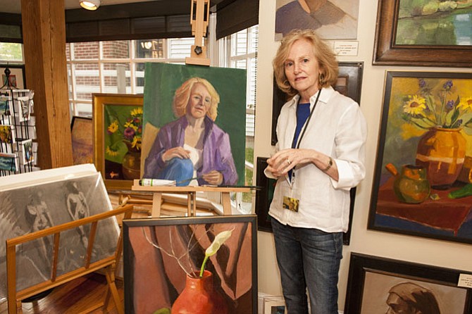 Painter Judith St. Ledger-Roty alongside a self-portrait, a nearly finished work in progress.