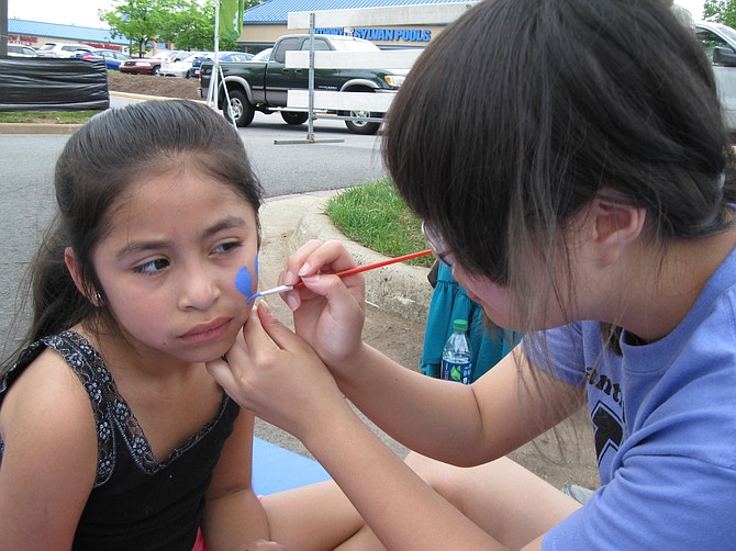 Vanessa Andrade, 7, gets her face painted by Yesong Song, a 10th-grader at Chantilly High School.
