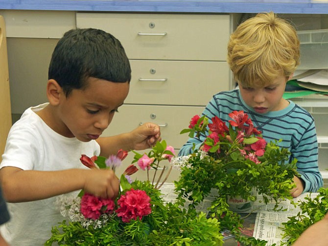 Two preschoolers in the garden therapy class at Glebe Elementary focus on the final touches of their hummingbird arrangement. 
