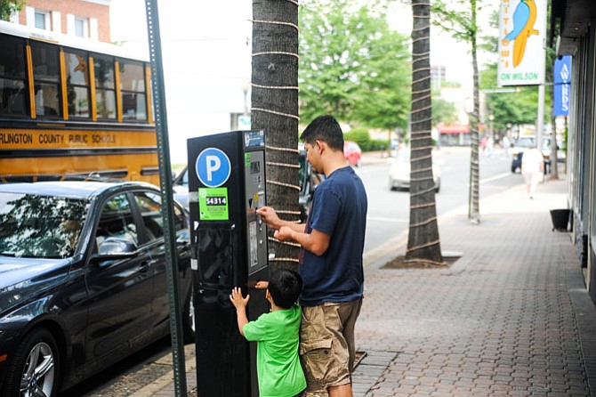 Christian Juarez with his son paying a meter in Clarendon. Photo by Connor Ortman/The Connection