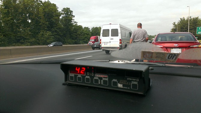 Master Police Officer Joe Moore approaches the driver’s side of a vehicle while the radar system in his police cruiser registers the speed of cars passing directly next to the shoulder.