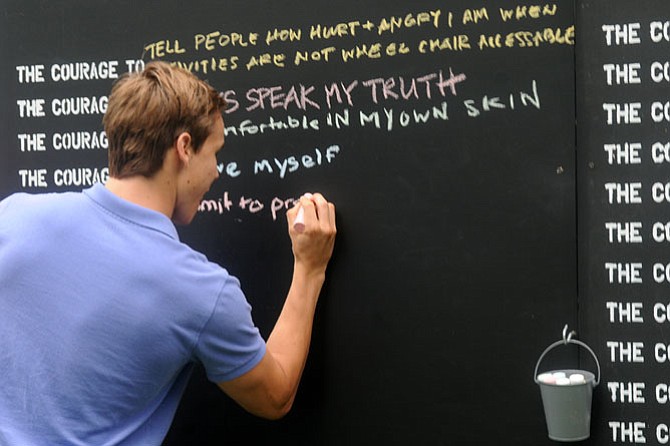 A young man passing by adds his thoughts on courage to the Wall.