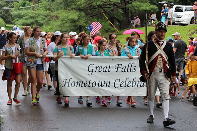 Mark Casso leads the parade with area Girl Scouts. Despite a 30-minute rain delay, hundreds of people participated in the festivities.
