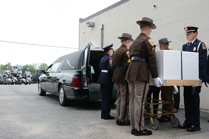 An honor guard representing multiple police and firefighting forces lifts the packaged casket of Brazilian Investigator Carlos Silva, who died in a bicycle accident during the World Police and Fire Games.