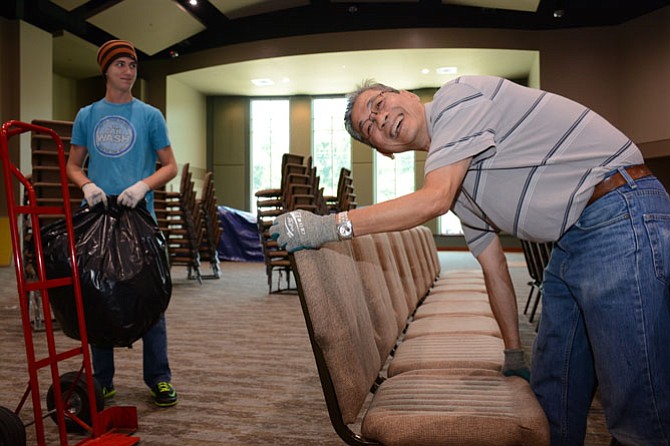 Rising South County senior and Christ Church member Patrick Richards (left) helps head custodian Phat Dang (right) set up chairs in the brand new 630-seat worship area.
