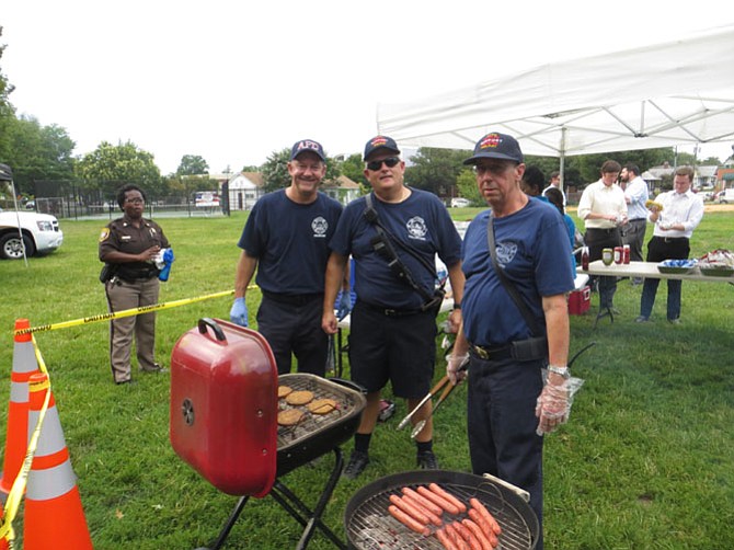 Mark Souder (left); Thomas “Jay” Johnson, president of the Volunteer Fire Department (center); and Willie Squires (right) cook hotdogs and hamburgers outside the Mount Vernon Recreation Center in Alexandria for National Night Out.
