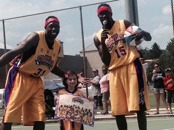 Tenley Schvimmer, 6, poses in her new prize jersey with Harlem Wizards John Smith and Lloyd Clinton