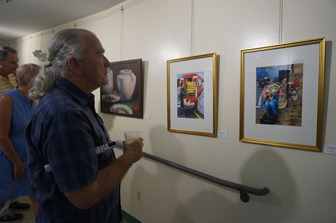 Artist Tom Kirby studies some of the entries on display at the Young At Art opening reception at the Durant Center Aug. 26. 
