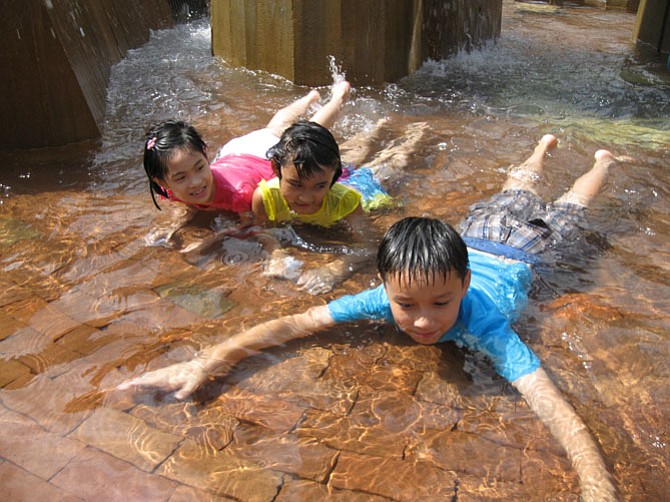 Helen Nguyen, Katie Phan and Christopher McMullen enjoy playing in the water fountain during the Lake Anne Jazz Festival.