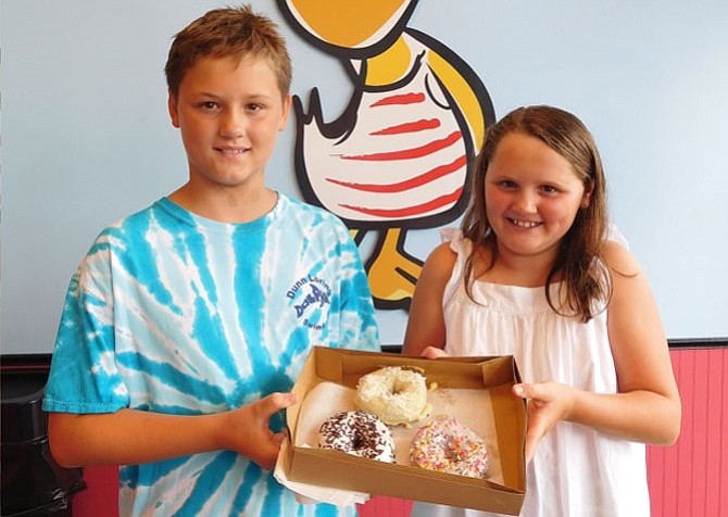 Siblings Bo and Emma Lewis show off their doughnuts – strawberry-frosted with rainbow sprinkles, vanilla with chocolate sprinkles and lemon with coconut.