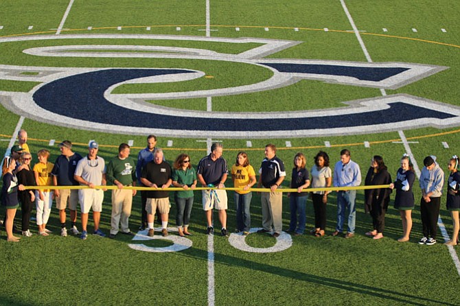 Community leaders, faculty and students gather to cut the ribbon formally dedicating the new artificial turf competition field at South County High School.