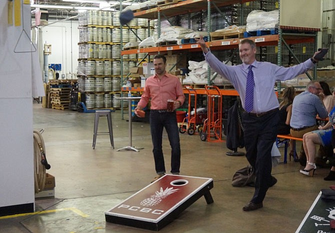 Burke and Herbert’s Joe Collum, right, takes on Jeffrey Feller in the cornhole tournament.
