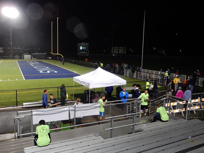Several runners by the bleachers, with drinks and snacks, after completing their race.
