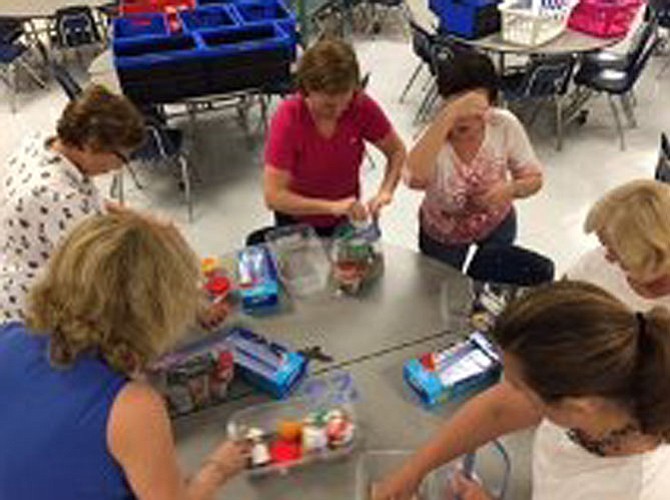 From left, Diane Brooks, Linda Gower, Emily Wild, Dina Koch, Karen Clark and Jennifer Forsythe assemble food packs at the Woodley Hills Elementary School community packing event.
