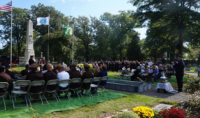 Fire Chief Robert Dube, at podium, leads a round of applause for Alexandria’s firefighters and EMS first responders during the Oct. 9 ceremony at Ivy Hill Cemetery.