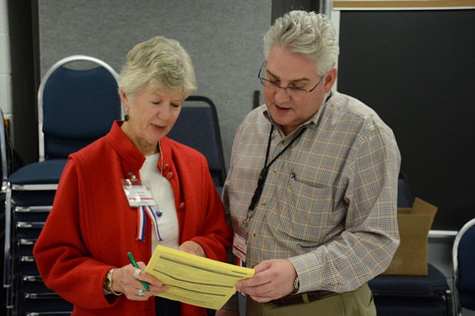 West Springfield High School precinct chief election officer Allyn Hammel of Burke (left) and her assistant Bill Batterson of Springfield (right) review election day materials in the West Springfield cafeteria on Nov. 3.