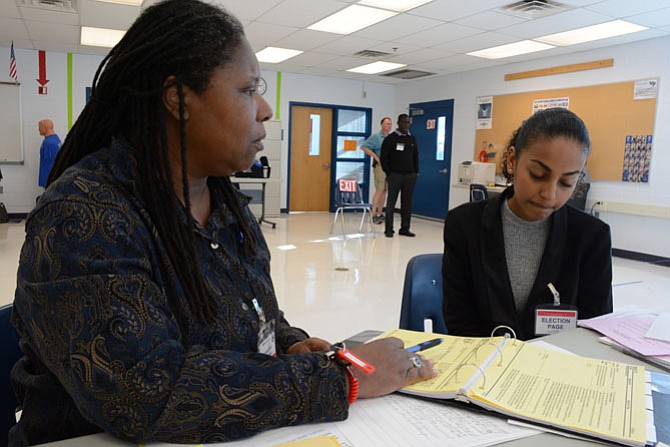 West Potomac High School chief election officer Doris McBryde of Mount Vernon (left) goes over polling location guidelines with election page Elham Mohaba (right) a sophomore at Thomas Edison High School.