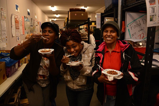 From left, Lorton residents Abena Kodua, Ruth Bioh and Oneida Monterrosa enjoy a bowl of venison chili after picking up groceries at the Lorton Community Action Center.