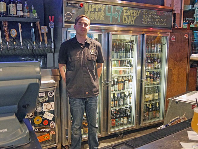 Will Bruder stands in front of the case of over 300 bottles of beer at Rustico’s. He says they also offer 30 beers on tap with IPAs, Pilsners and Belgium Wits the most popular.
