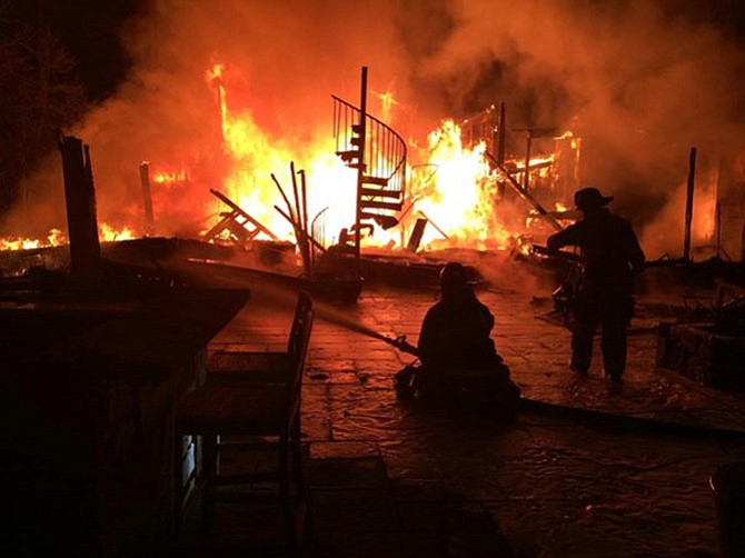 Firefighters attack the Great Falls blaze with hoses. The house was vacant and for sale.
