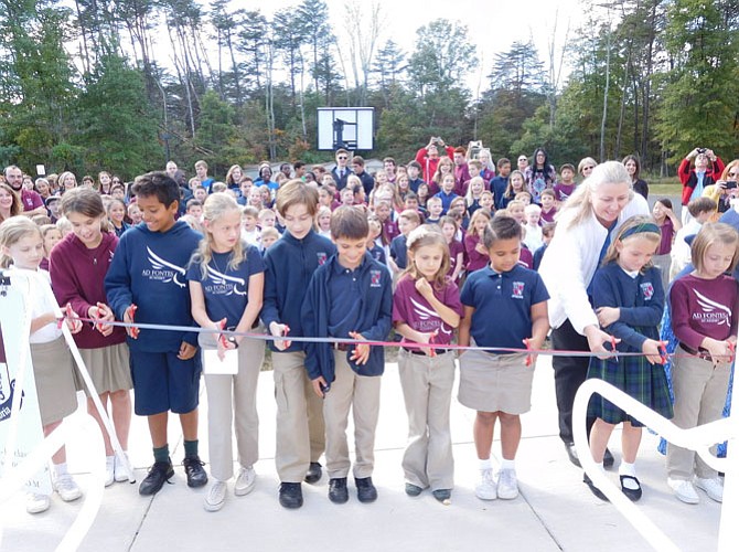 Ad Fontes students cut the ribbon on the new building with Lower School Office Manager Joan Druessel.
