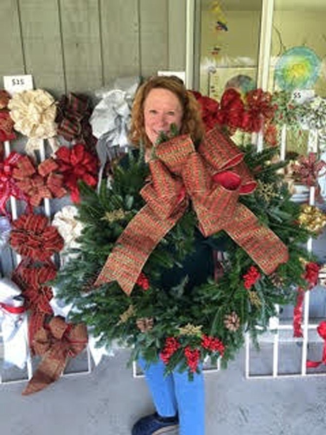 Jean Krause, mother of St. Aidan’s Episcopal Church member Wynne Kelch, sets out a large, decorated wreath at the church’s wreath and Christmas tree sale.