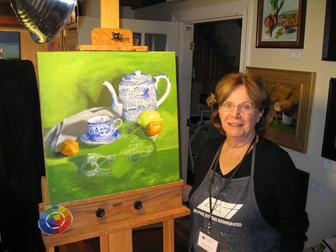 Fine artist Carol Howard, who works at Artists' Atelier in the Great Falls Village Center in Great Falls, with two of her recent pieces.
