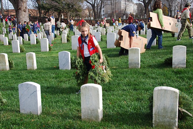 Jane Bremberg looks for a headstone to place a wreath.
