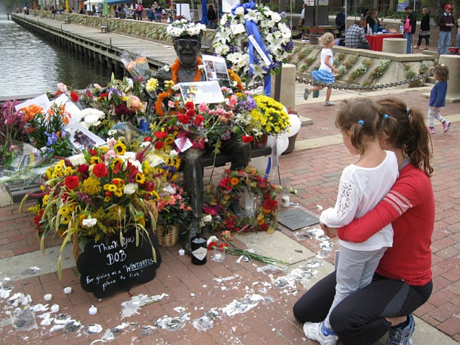 The statue of Reston founder Robert Simon at Lake Anne Plaza is covered in flowers after his death Sept. 21.
