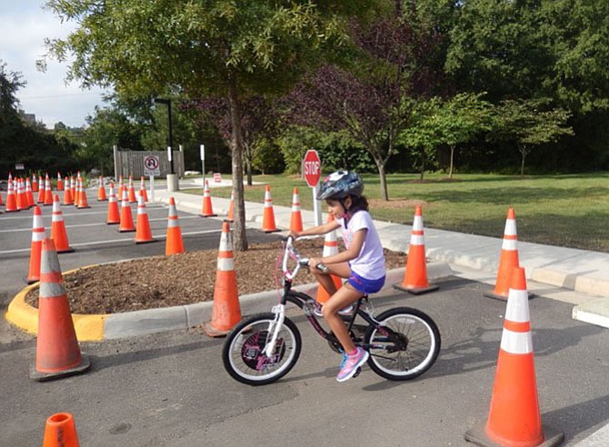 Liliana Silva, who attends St. Leo the Great Catholic School, bicycles through the safety-cone course at a Kids’ Safety Day held by the City of Fairfax Police Department. 
