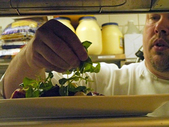 After adding the roasted onion garnish, traditional for beef bourguignon, Chef Graham Duncan finishes his vegan spinoff dish with a little bit of fresh mache and leaves it on the order tray for delivery to the lunch customer.
