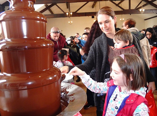 Lily Mae Hamilton, 5, happily dips a treat into the chocolate fountain while mom Lora Ann and brother Jack, 1, watch.
