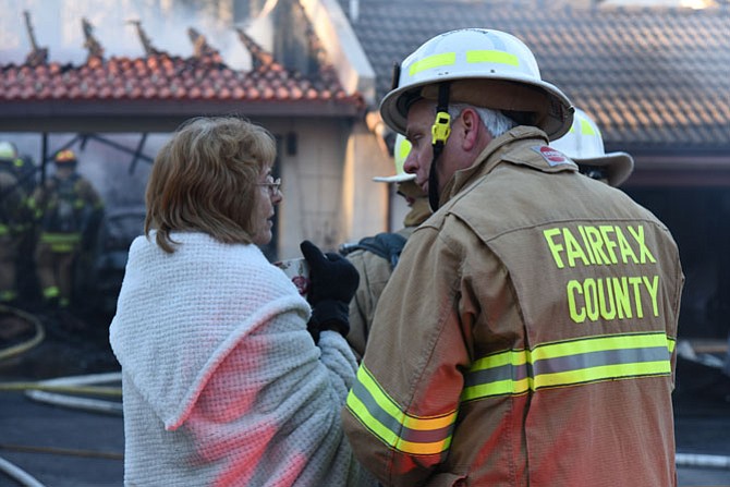 Captain John Nimiec, of Fairfax County Fire and Rescue, comforts Judy Kilmartin, whose house was damaged by fire on Feb. 18 in Reston.
