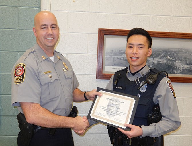Capt. Bob Blakley (left) presents the Officer of the Month award to Officer John Hong.
