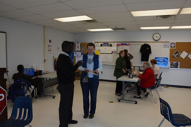 Election Officer Evans Appinh (left) of Mount Vernon verifies Jennifer Morris (right) of Mount Vernon has the correct ballot and then directs her to use a booth designated for that political party affiliation.