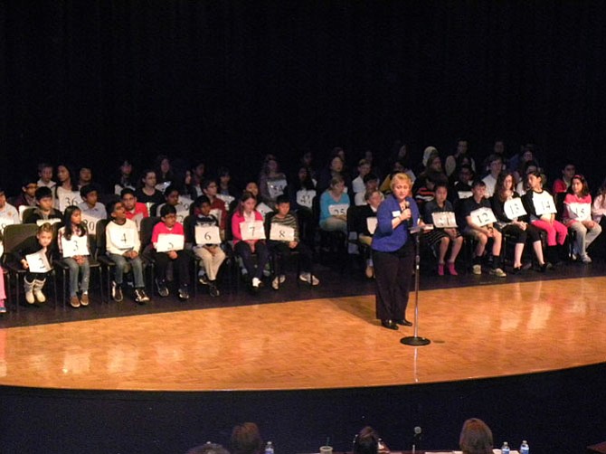 Debbie Kilpatrick, president of the Fairfax County Council of PTAs, thanks sponsors of the 10th Fairfax County Spelling Bee. Behind her are the 62 participants of the Bee.
