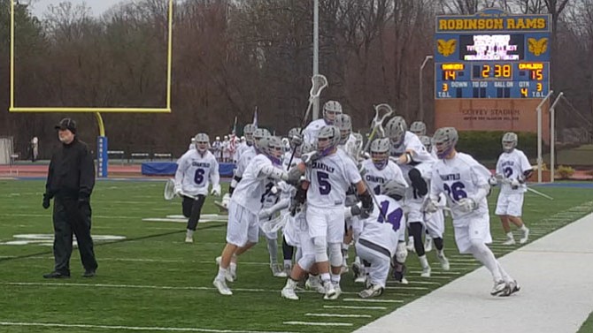 Members of the Chantilly boys’ lacrosse team celebrate Colin Meehan’s (5) game-winning goal against Woodson on March 19.