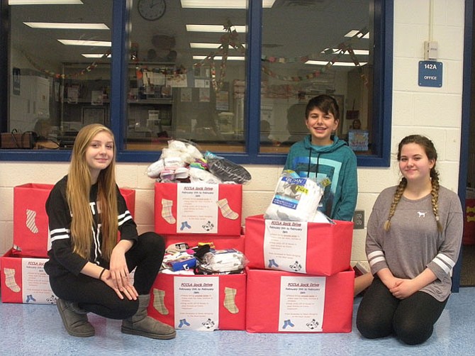 (From left) are Lanier students Jules Welch, Sami Saghir and Nora Farid with the boxes full of socks they collected.
