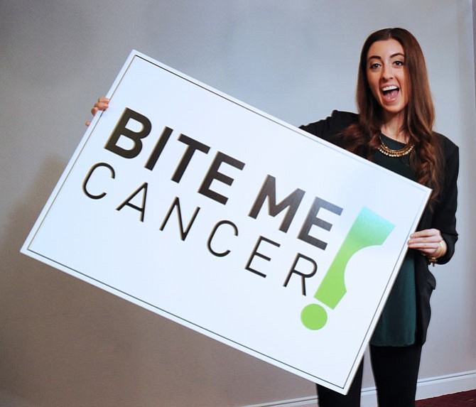 Bite Me Cancer founder Nikki Ferraro holds a poster-size photo of her foundation’s new logo unveiled Thursday, March 31, at Bite Me Cancer’s annual investors breakfast held at the group’s headquarters in the  Fair Lakes Area of Fairfax. Bite Me Cancer, a national foundation that supports teens with cancer and raises funds for thyroid cancer research, also  went live with its redesigned website (www.bitemecancer.org) this week.
