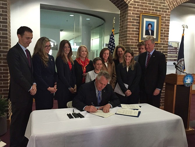 Flanked by gun-control advocates and Alexandria city officials, Gov. Terry McAuliffe signs a series of vetoes against legislation that would make it easier for victims of domestic abuse to obtain concealed weapons.
