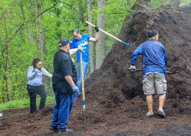 Volunteers tackle a mound of mulch. By the end of the event, they got it spread all around the parking lot and picnic areas.

